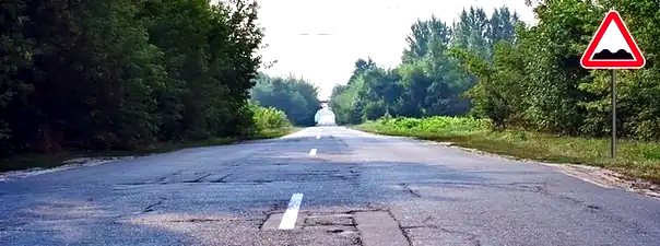 Иллюстрация к вопросу: На каком расстоянии до неровного участка дороги устанавливается этот знак вне населённого пункта?